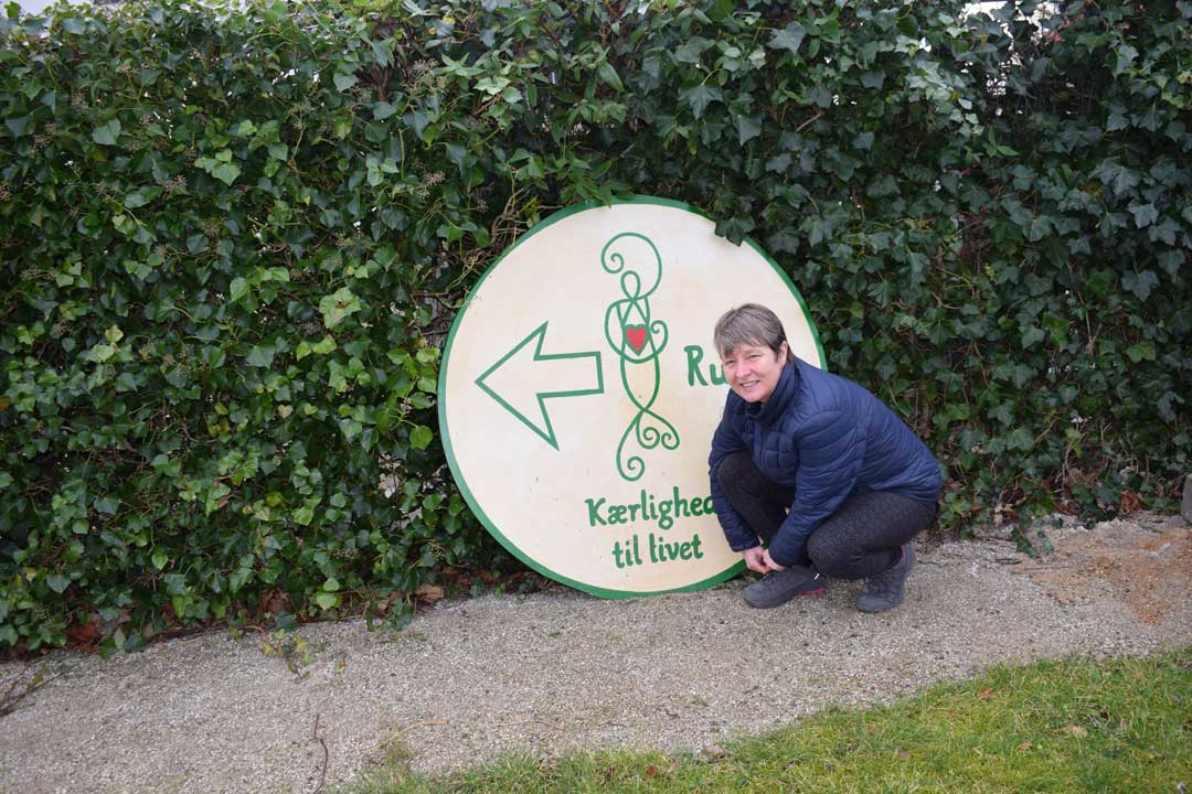 Tine foran det flotte Kærlighed til livet-logo, der med en pil viser startretningen på den lokale ”pilgrimsrute”.
